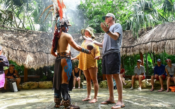 Couple participating in a traditional ceremony with a local guide in Cancun.