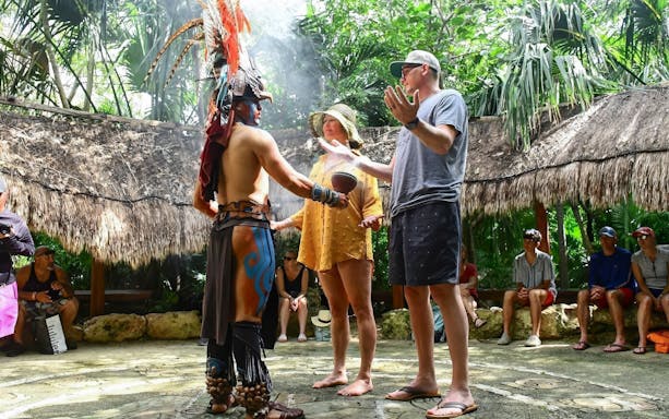 Couple participating in a traditional ceremony with a local guide in Cancun.