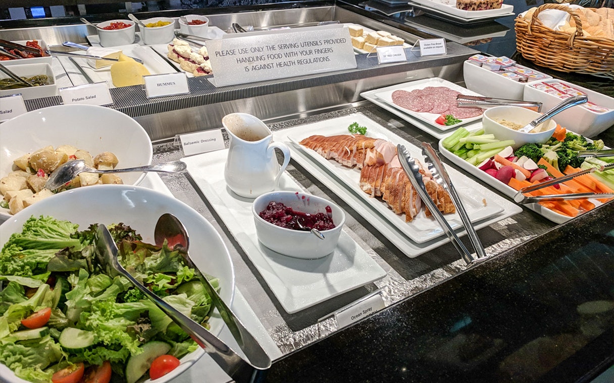 Buffet spread at Plaza Premium Lounge with salads, cold cuts, and condiments.