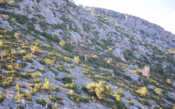 Person ziplining over rocky landscape in Split, Croatia.