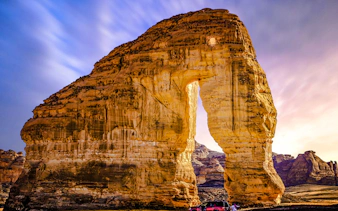 Elephant Rock in AlUla, Saudi Arabia, with a car parked nearby at sunset.