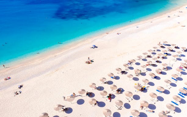 Sun umbrellas and loungers on Assos Beach, Kefalonia Island, Greece.