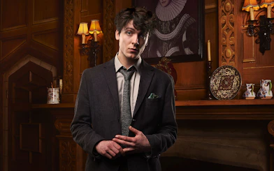 Man in a suit standing in a vintage room with ornate wood paneling, related to The Mousetrap.