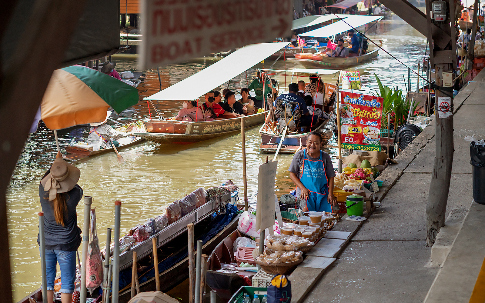 Boats and vendors at Amphawa Floating Market, Thailand.
