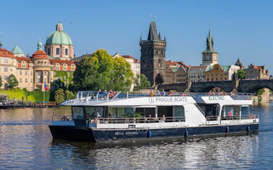 Cruise boat on Vltava River passing Charles Bridge in Prague.
