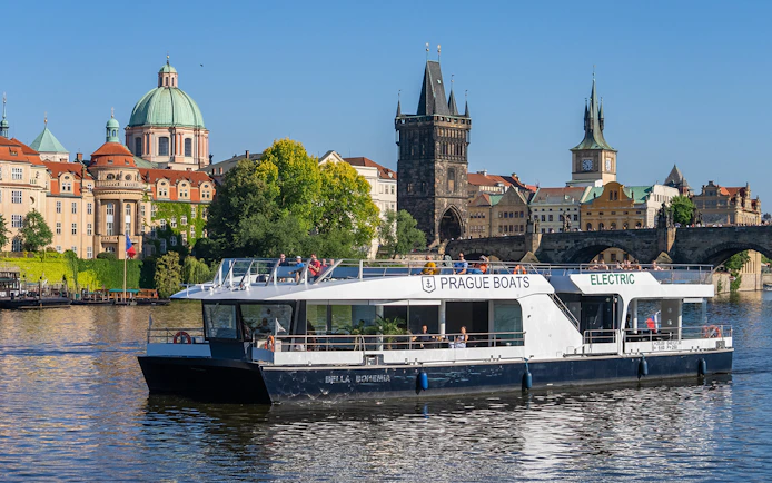 Cruise boat on Vltava River passing Charles Bridge in Prague.