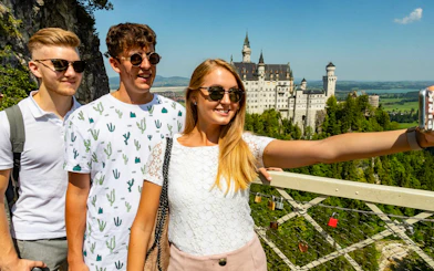 Tourists taking a selfie with Neuschwanstein Castle in the background, Bavaria, Germany.