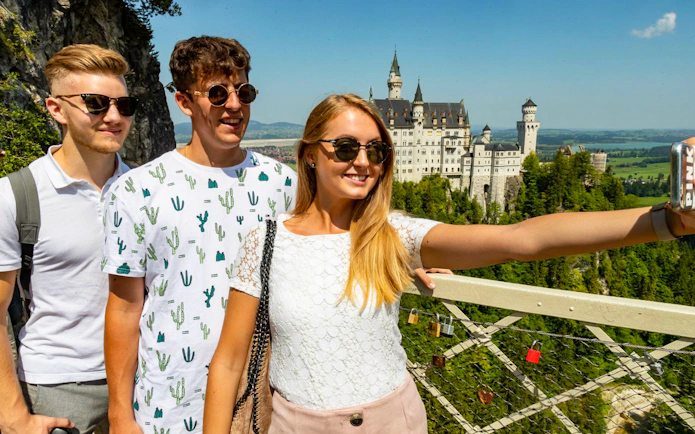 Tourists taking a selfie with Neuschwanstein Castle in the background, Bavaria, Germany.