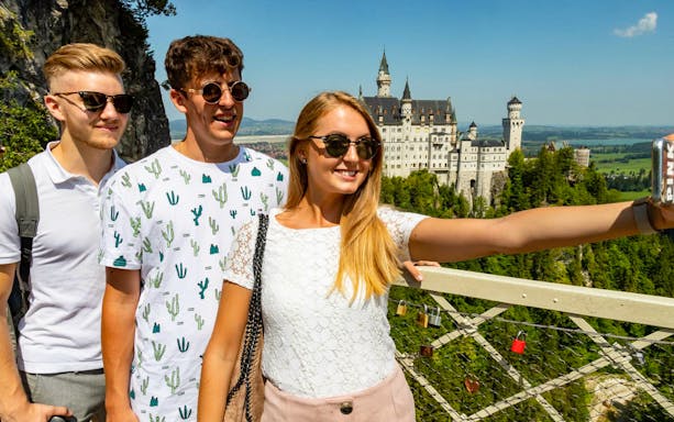 Tourists taking a selfie with Neuschwanstein Castle in the background, Bavaria, Germany.