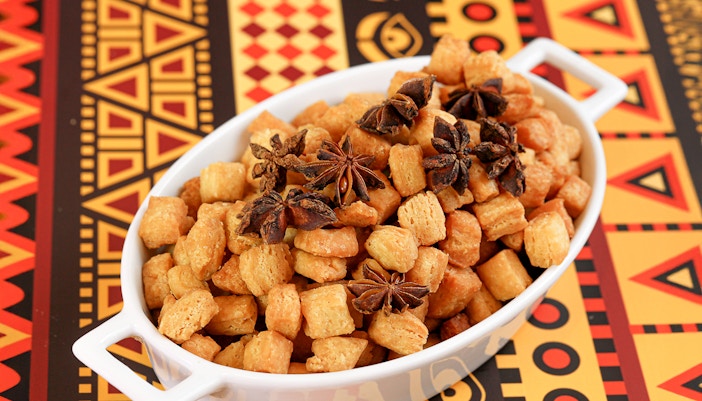 Chin Chin in a white bowl with star anise on a colorful African-patterned tablecloth.