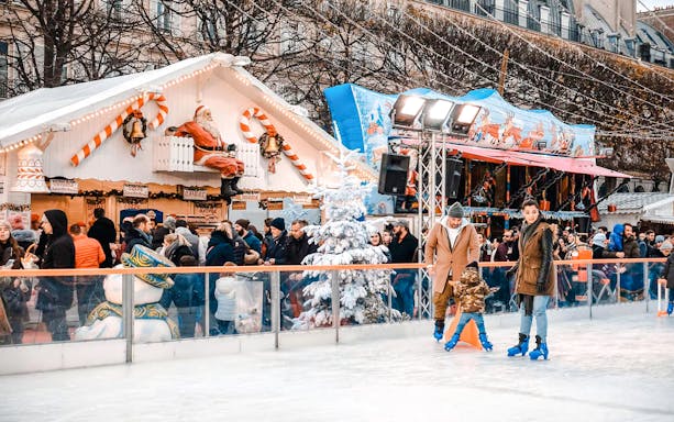 Ice skating at Paris Christmas Market with festive stalls and decorations.