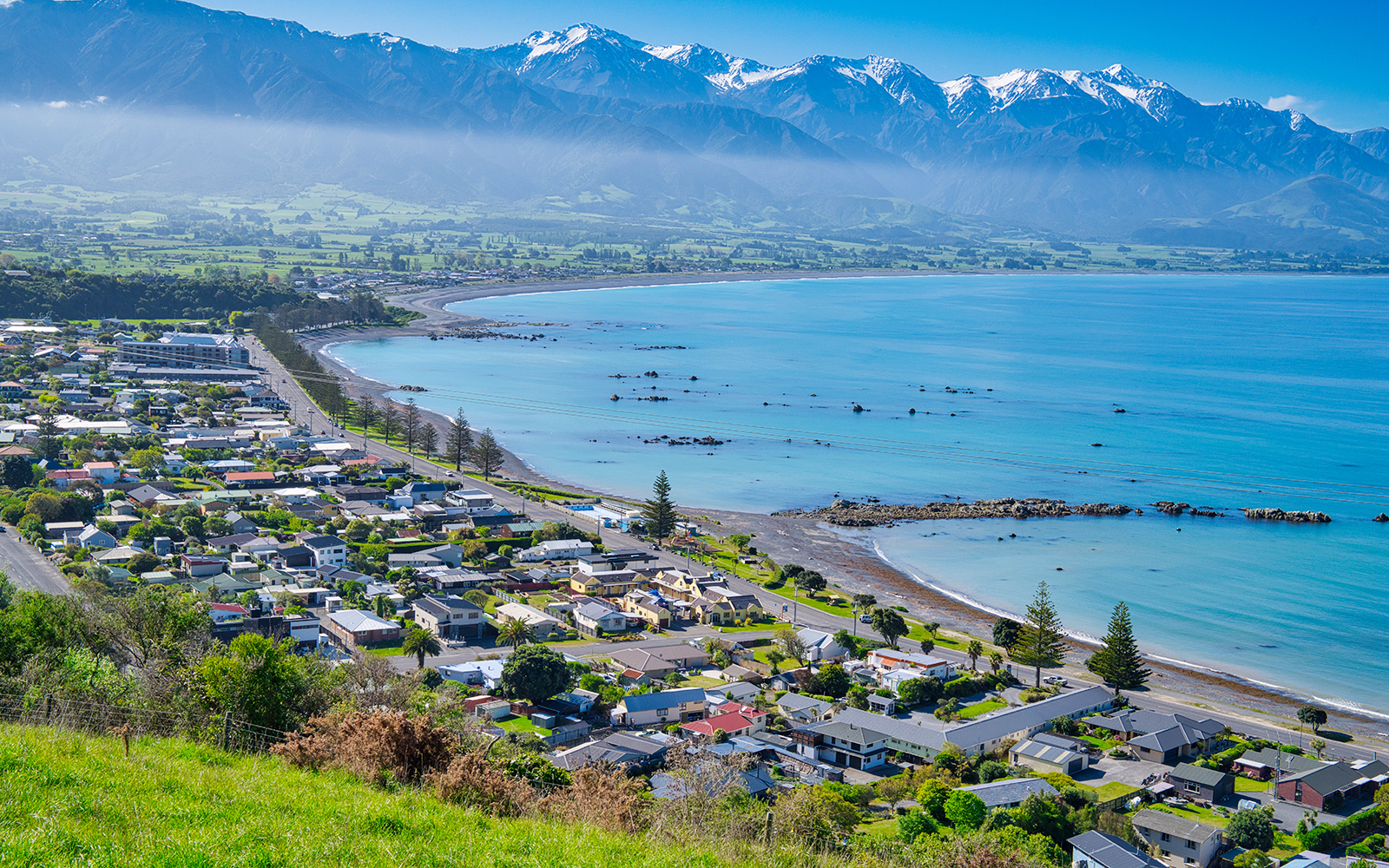 Coastal town of Kaikoura, New Zealand with mountains and ocean in the background.
