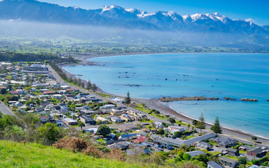 Coastal town of Kaikoura, New Zealand with mountains and ocean in the background.
