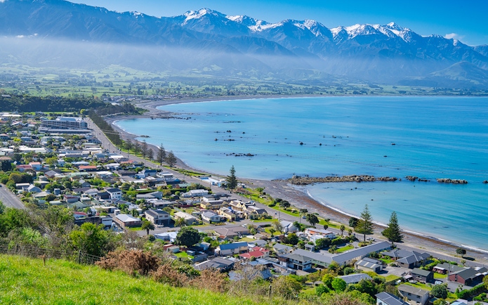 Coastal town of Kaikoura, New Zealand with mountains and ocean in the background.