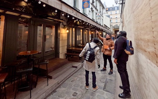 Tour guide showing Emily in Paris filming location at Pub St Germain, Paris.