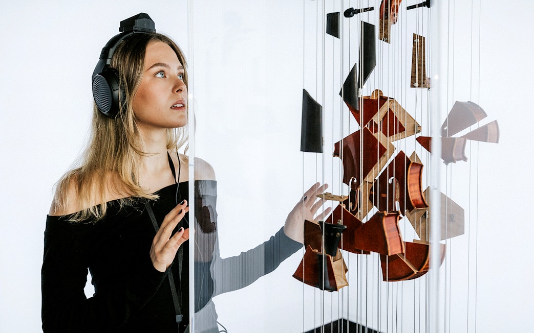 Visitor at Vienna's Johann Strauss Museum engaging with interactive violin exhibit.