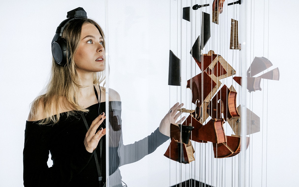 Visitor at Vienna's Johann Strauss Museum engaging with interactive violin exhibit.