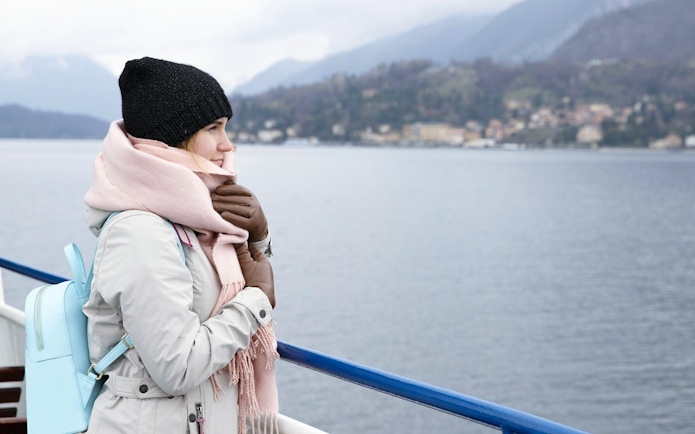Tourist on a cruise ship in Iceland, viewing scenic coastal landscape.