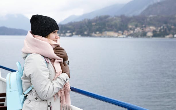 Tourist on a cruise ship in Iceland, viewing scenic coastal landscape.