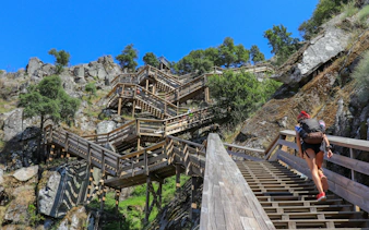 Woman ascending wooden stairs on Paiva Walkways with backpack, Portugal.