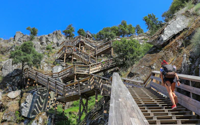 Woman ascending wooden stairs on Paiva Walkways with backpack, Portugal.