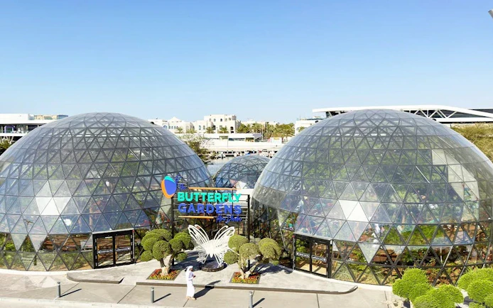 Butterfly Gardens Abu Dhabi glass domes with entrance and butterfly sculpture.