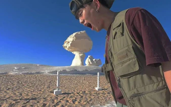 Person posing with rock formations in Egypt's Black and White Desert during a safari tour.