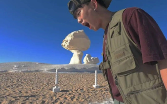 Person posing with rock formations in Egypt's Black and White Desert during a safari tour.