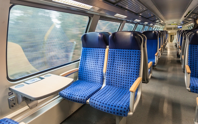 Interior of modern train with blue seats and large windows.
