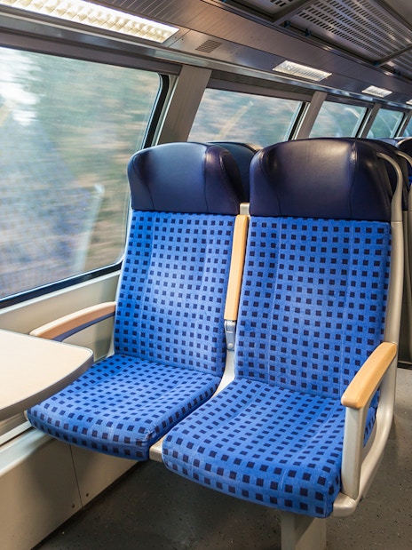 Interior of modern train with blue seats and large windows.