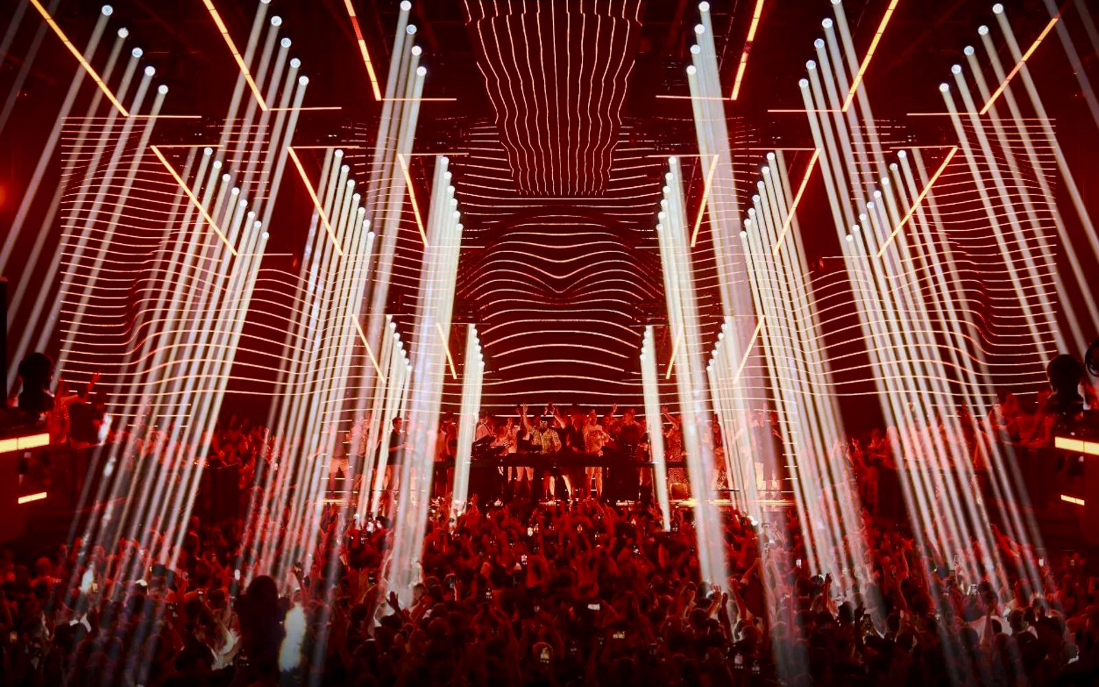 Crowd enjoying Fisher UNVRS performance with vibrant lights in Ibiza nightclub.