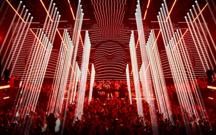 Crowd enjoying Fisher UNVRS performance with vibrant lights in Ibiza nightclub.
