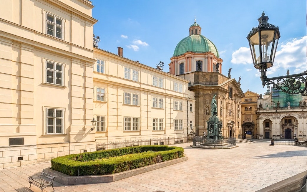 Historic square in Prague with statue and baroque architecture.