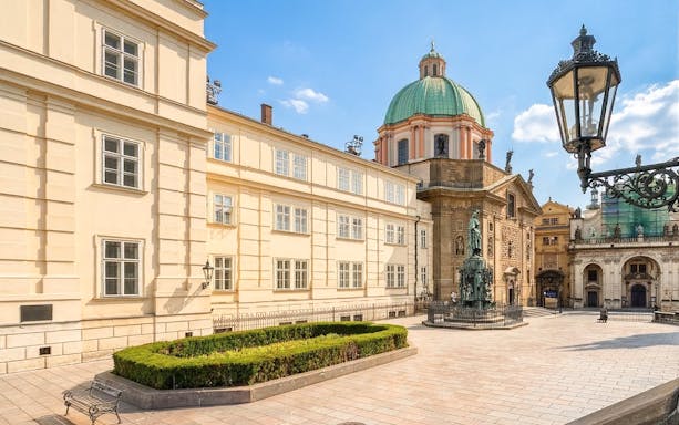 Historic square in Prague with statue and baroque architecture.