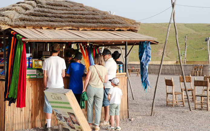 Visitors at a rustic food stall in Agafay desert camp, Morocco.