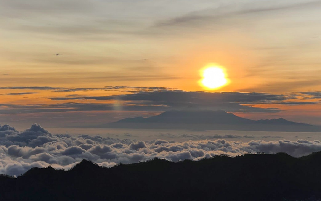 Sunrise view from Mount Batur with clouds and distant mountains in Bali.