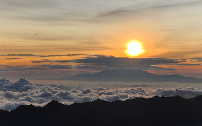 Sunrise view from Mount Batur with clouds and distant mountains in Bali.