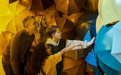 Guests interacting with colorful umbrella display at Twist Museum, London.