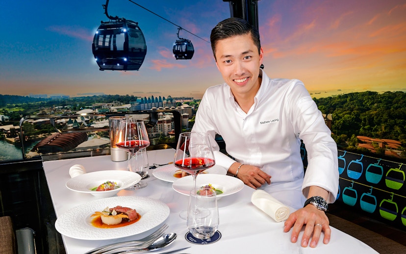 Singapore cable car dining with dishes by Chef Mathew Leong, overlooking city skyline.