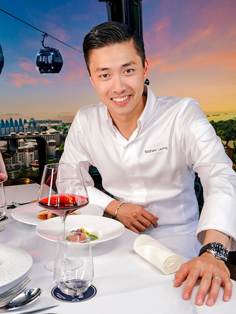 Singapore cable car dining with dishes by Chef Mathew Leong, overlooking city skyline.