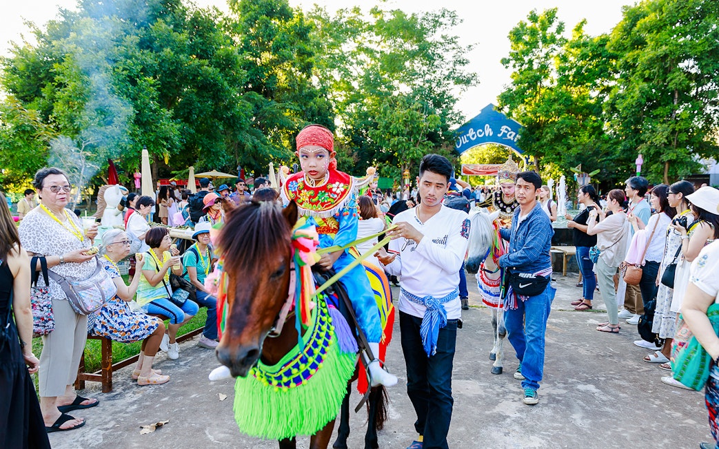 Young boy in traditional attire on a decorated horse at Chiang Mai Sky Lanterns Festival parade.