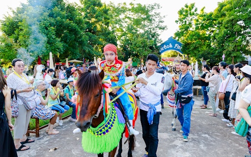 Young boy in traditional attire on a decorated horse at Chiang Mai Sky Lanterns Festival parade.