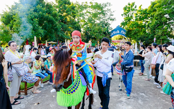 Young boy in traditional attire on a decorated horse at Chiang Mai Sky Lanterns Festival parade.