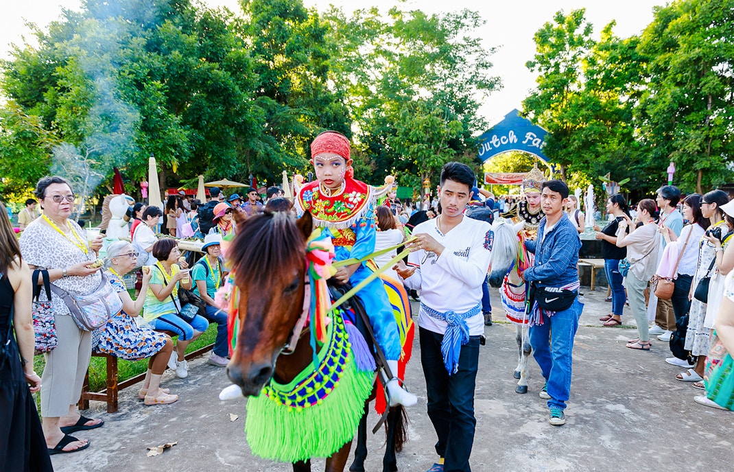 Young boy in traditional attire on a decorated horse at Chiang Mai Sky Lanterns Festival parade.