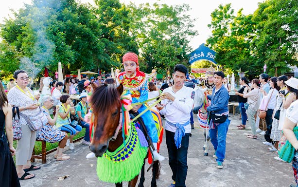 Young boy in traditional attire on a decorated horse at Chiang Mai Sky Lanterns Festival parade.