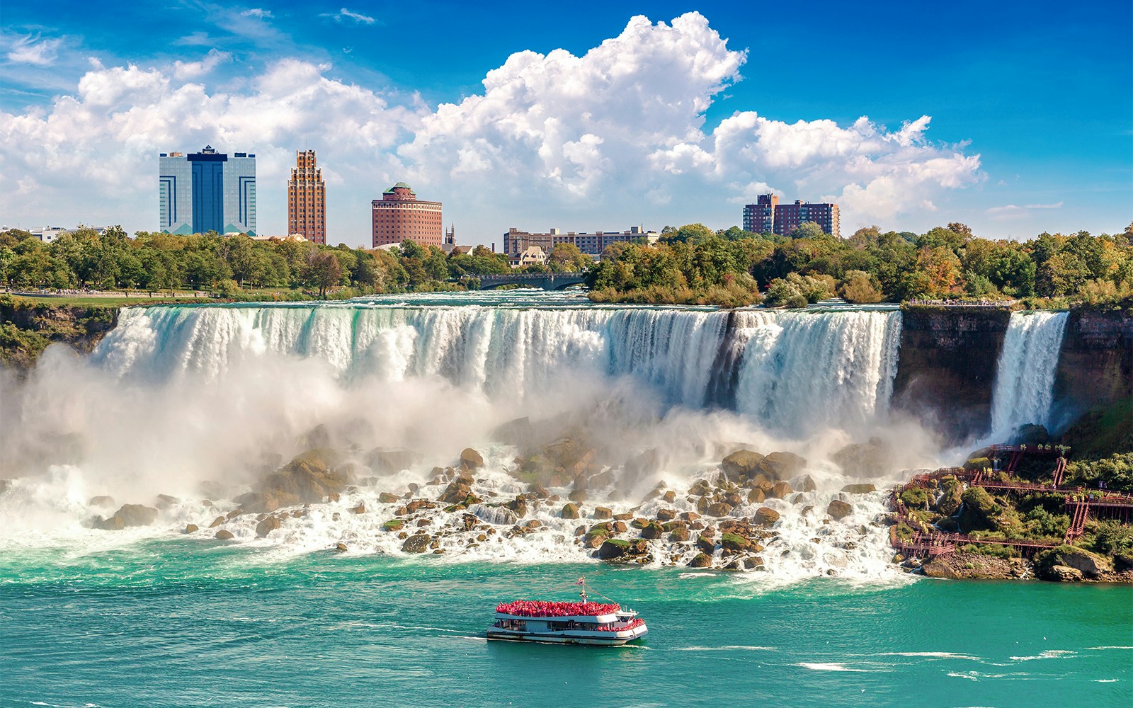 Hornblower Cruise boat approaching Niagara Falls, Canada with city skyline in the background.