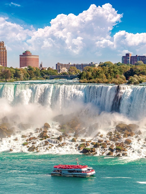 Hornblower Cruise boat approaching Niagara Falls, Canada with city skyline in the background.