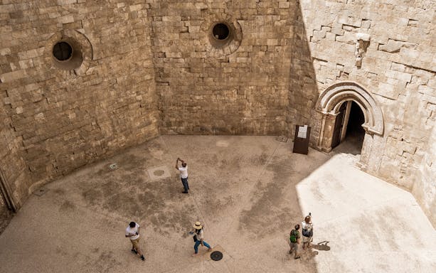 Visitors exploring the stone courtyard of Castel del Monte in Andria.