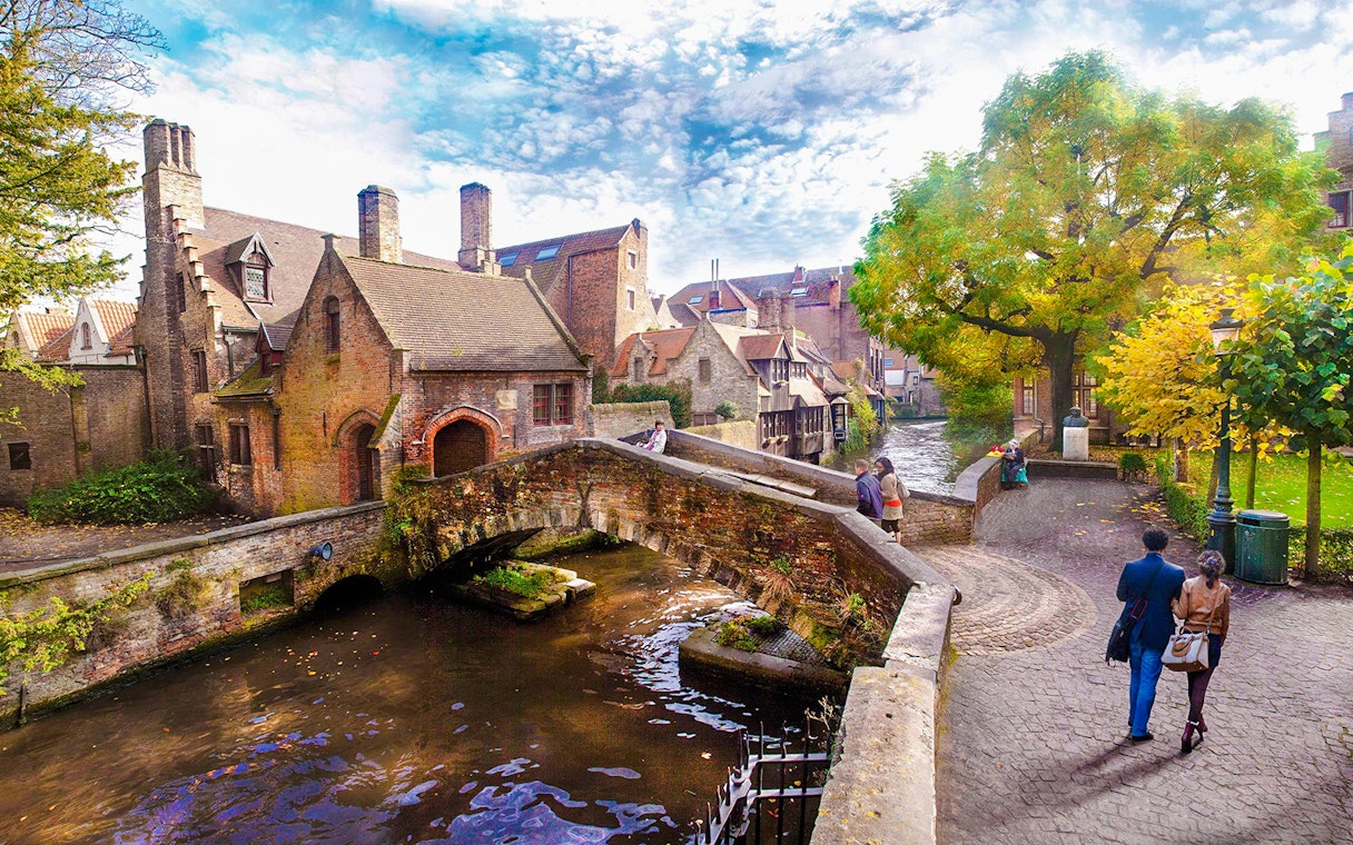 Boniface Bridge over canal in Bruges historic city center, Belgium, with people walking nearby.