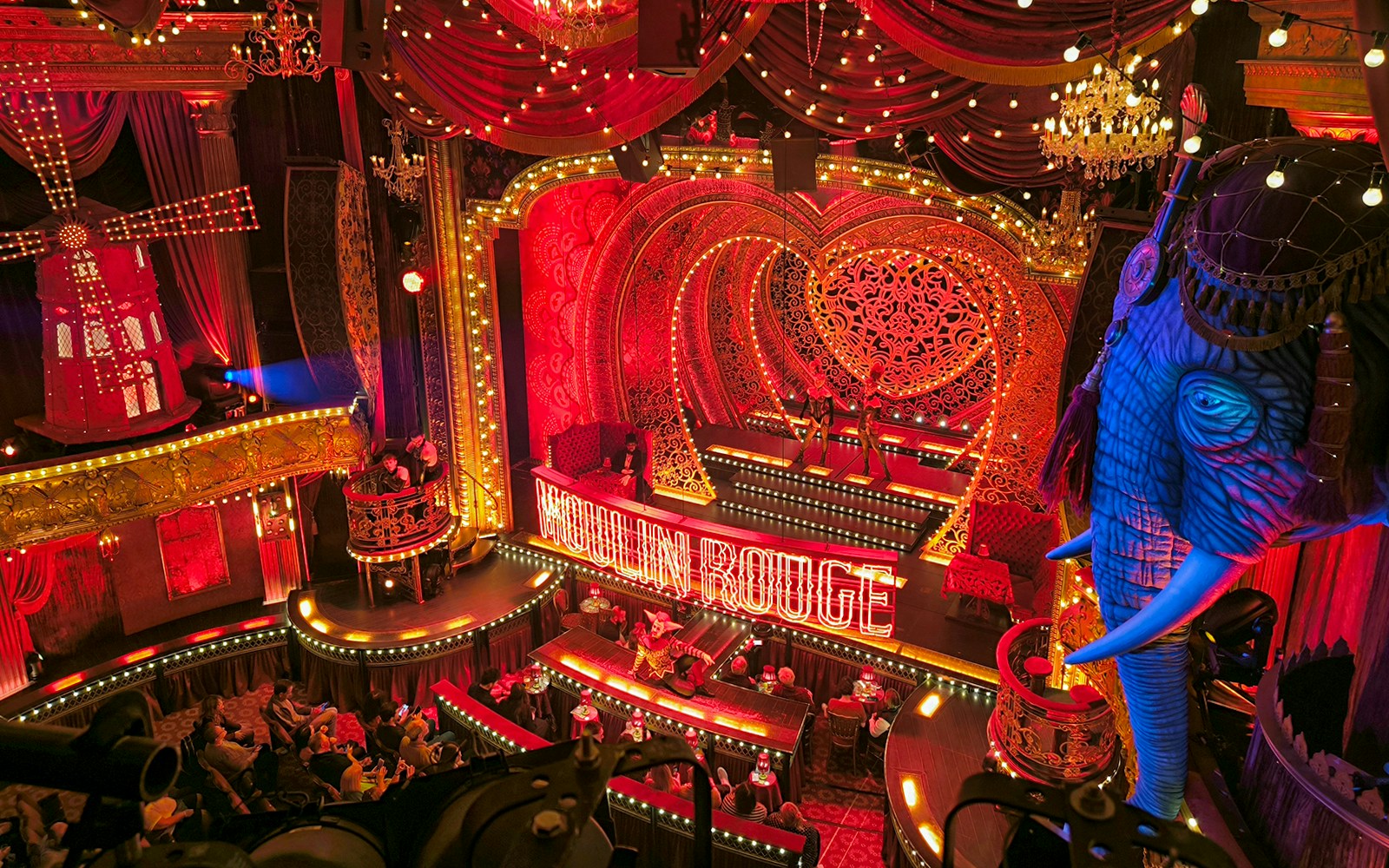 Moulin Rouge cabaret show in Paris with iconic red windmill and vibrant lights.